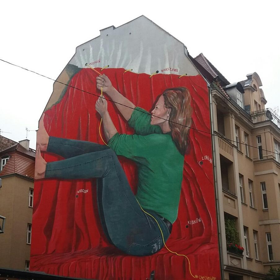 kobieta zszywająca flagę polski - mural w Poznaniu